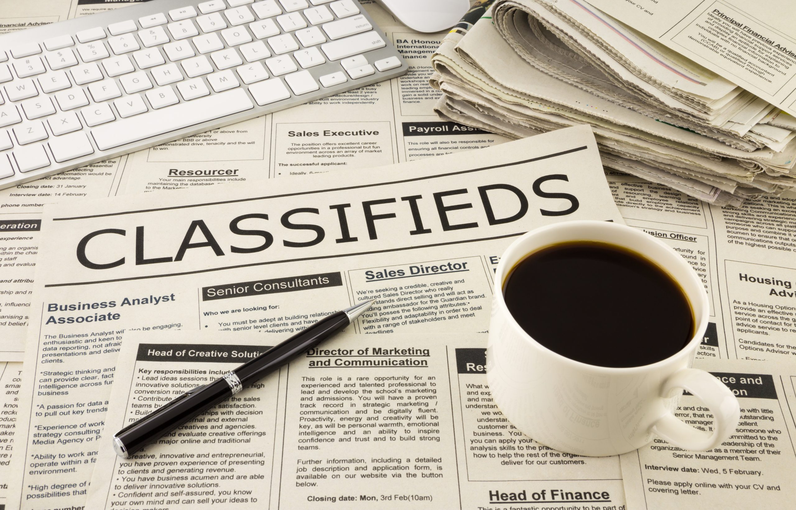 fake newspaper display classifieds advertising place on table with keyboard, pen and a cup of coffee